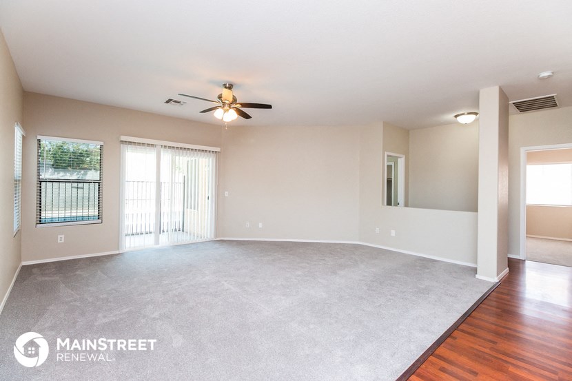 an empty living room with a ceiling fan