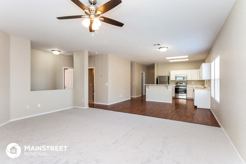an empty living room and kitchen with a ceiling fan