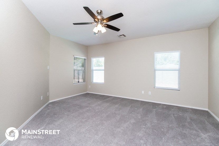 the spacious living room with ceiling fan and carpeting