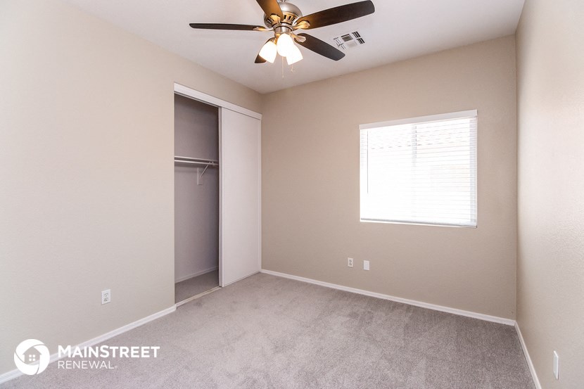 the spacious bedroom with closet and ceiling fan
