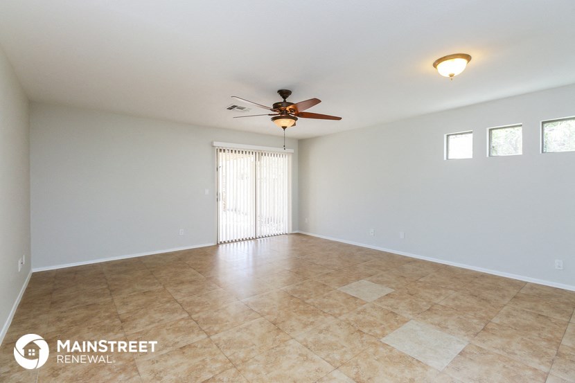 the spacious living room with tile flooring and ceiling fan