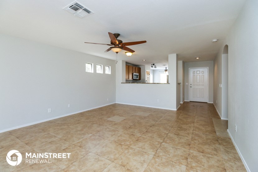 an empty living room with a ceiling fan and tile flooring