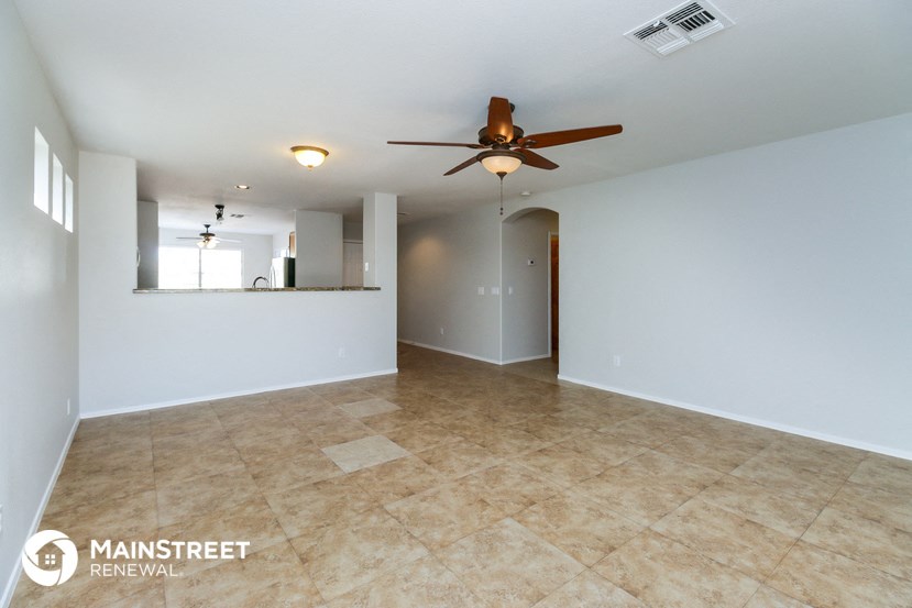 an empty living room with a ceiling fan and a tile floor