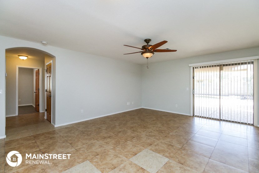 an empty living room with a ceiling fan