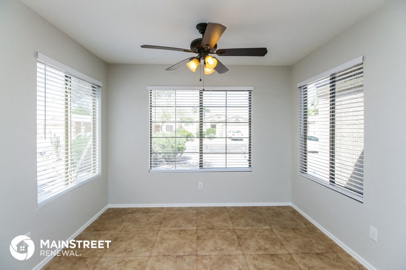 an empty living room with a ceiling fan and windows