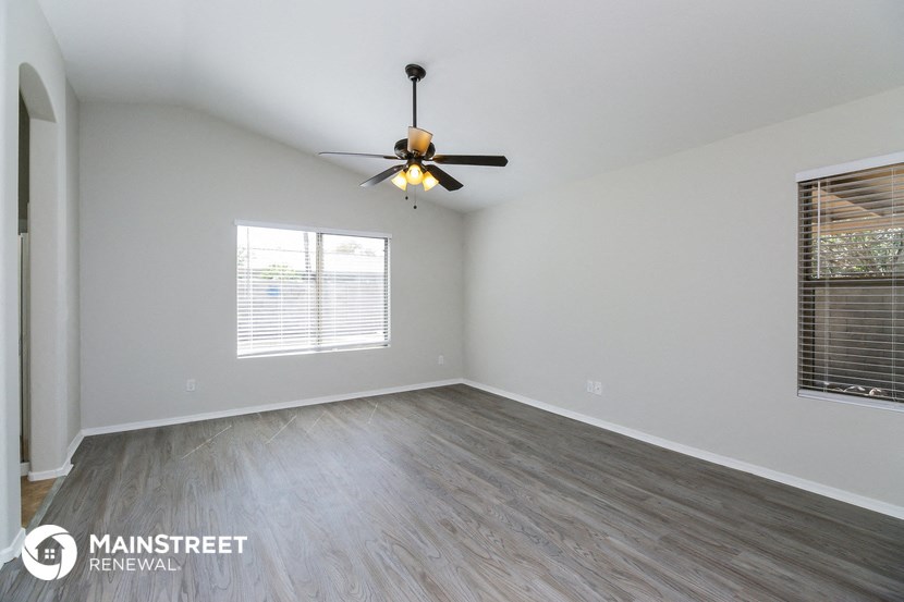 the spacious living room with wood flooring and a ceiling fan