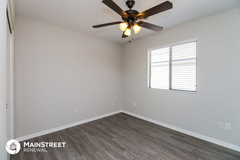 the spacious living room with ceiling fan and wood flooring