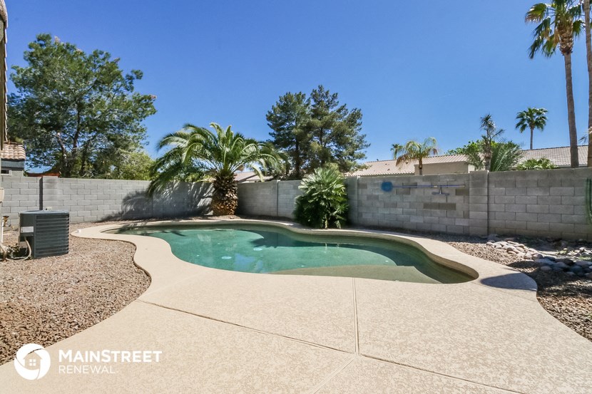 a pool in the backyard of a house with palm trees