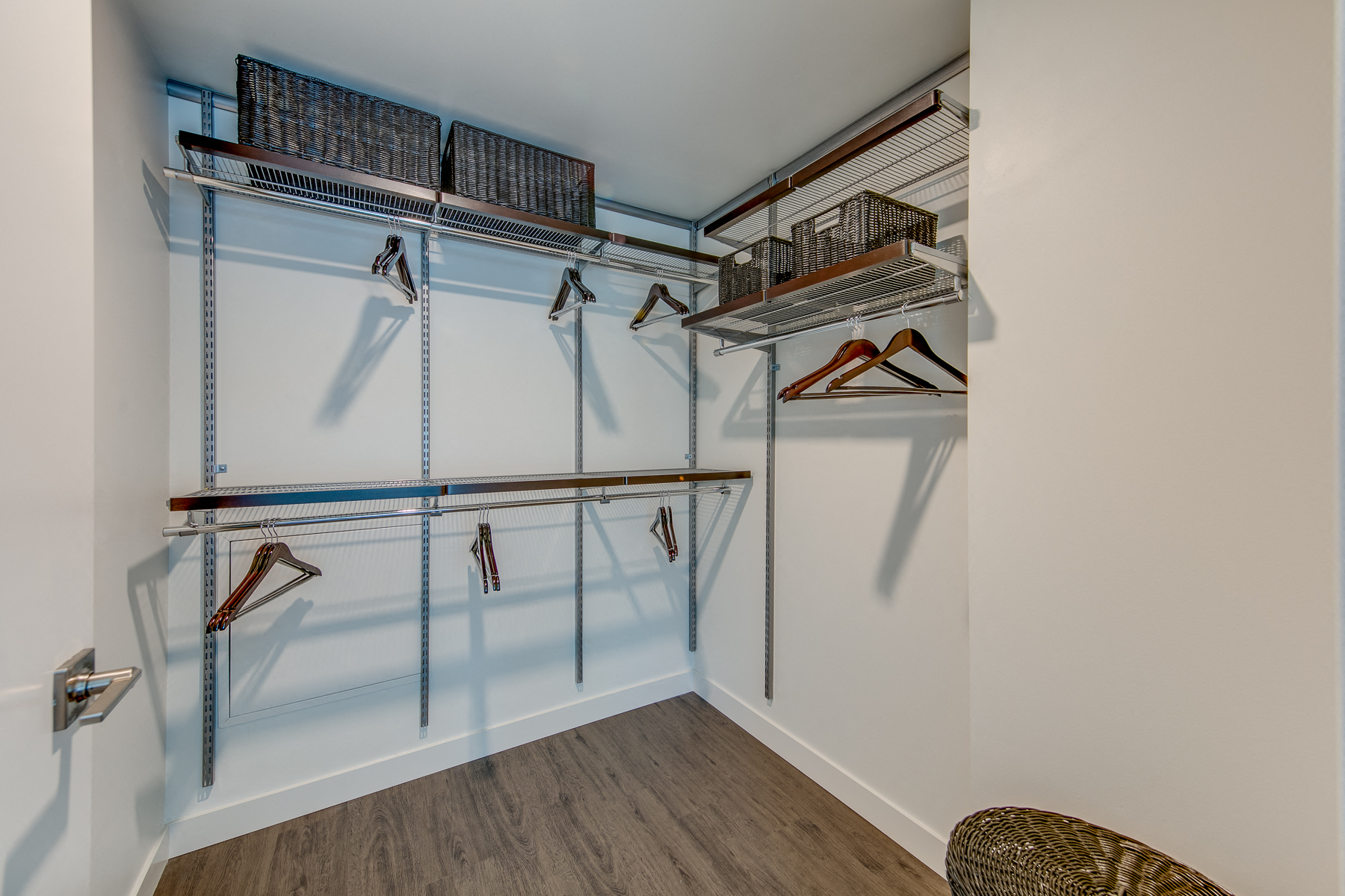 a spacious closet with shelving and hooks and a wicker chair