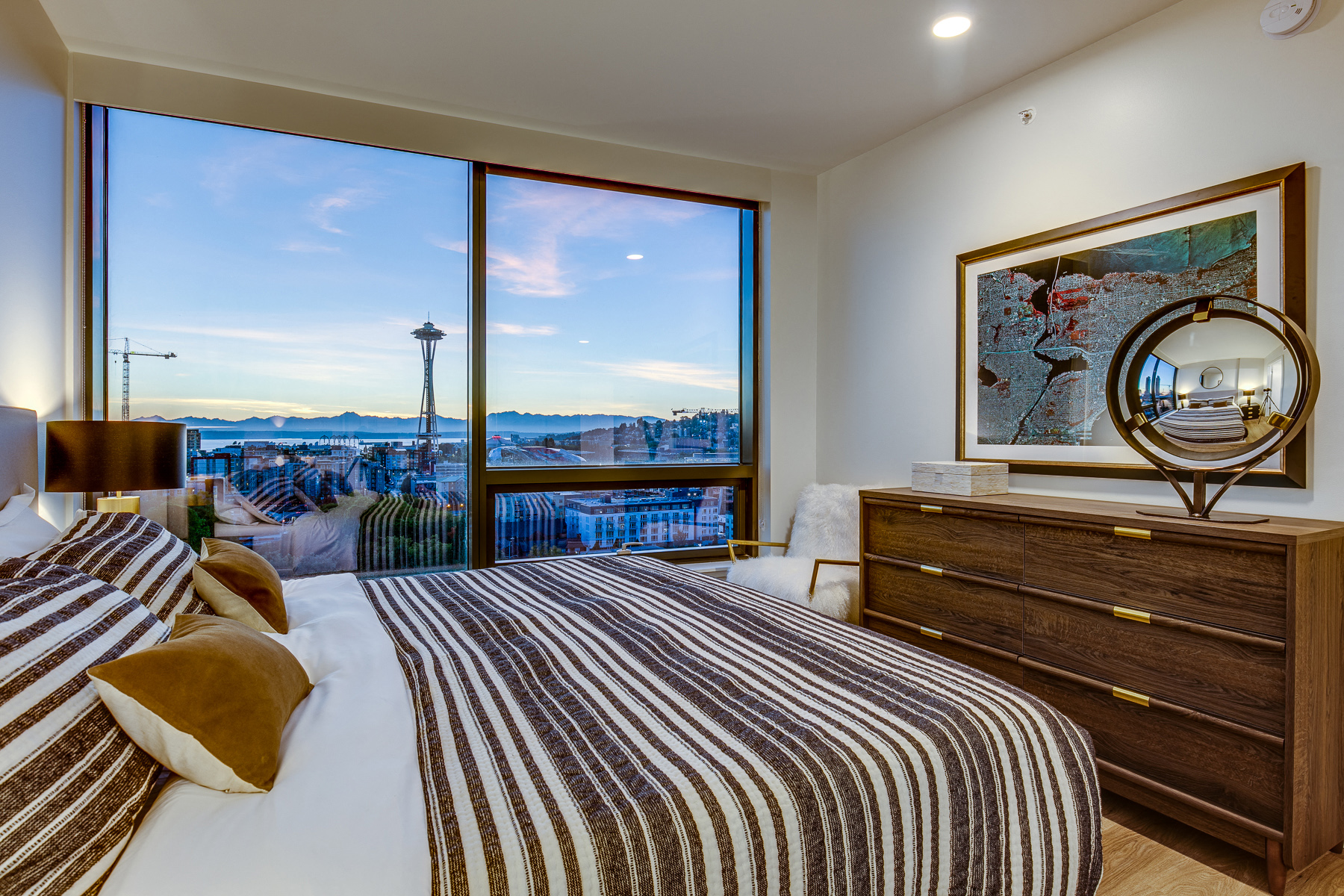 a bedroom with a bed and a large window with a city view