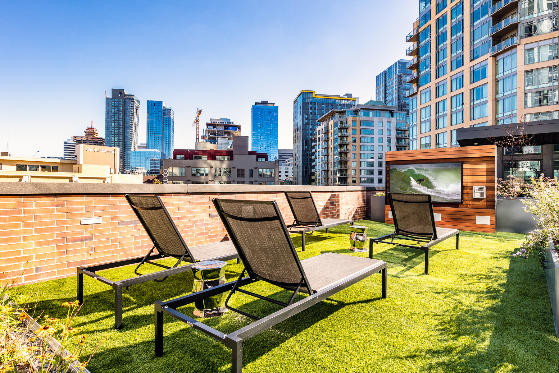 a roof terrace with chairs and a tv and a city in the background