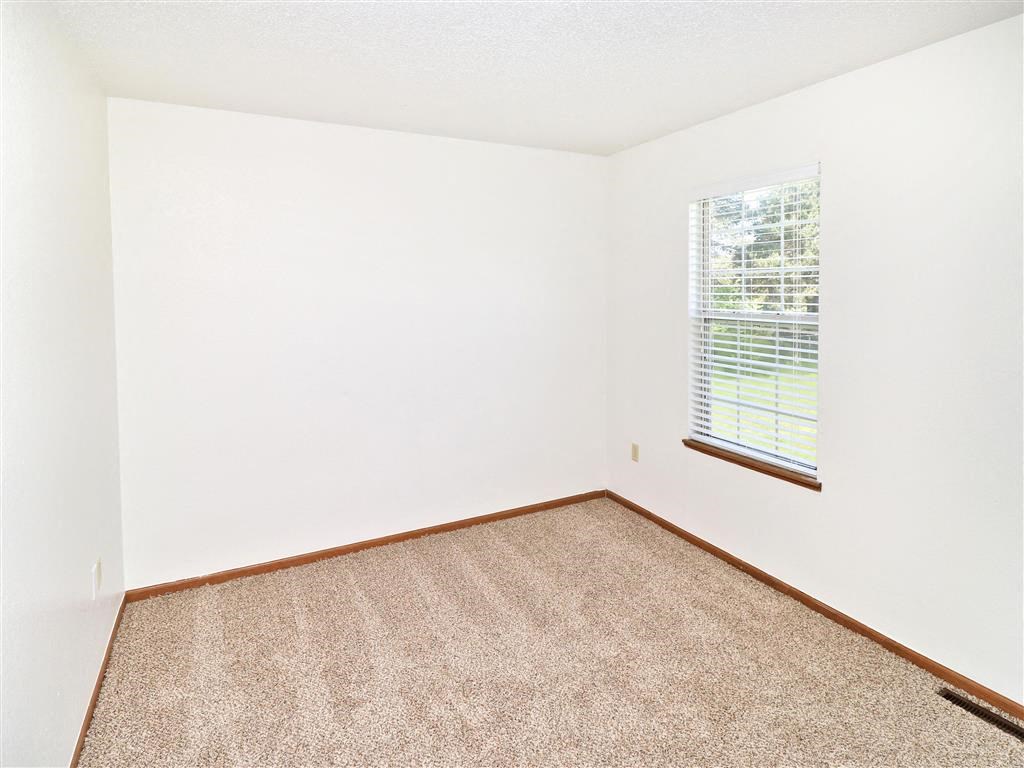 an empty room with a window and carpet