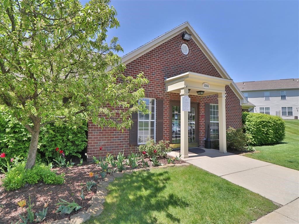 the front of a brick house with a tree and a sidewalk