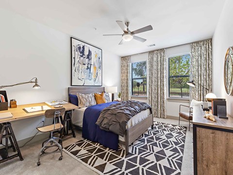 a bedroom with a bed and a desk and a ceiling fan