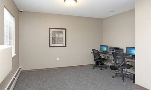 a room with two computer desks and a window