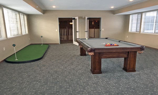 an empty billiards room with a pool table and a putting green