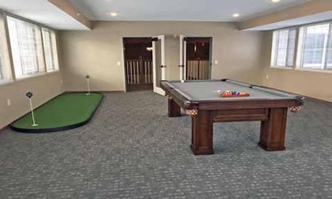 an empty billiards room with a pool table and a putting green