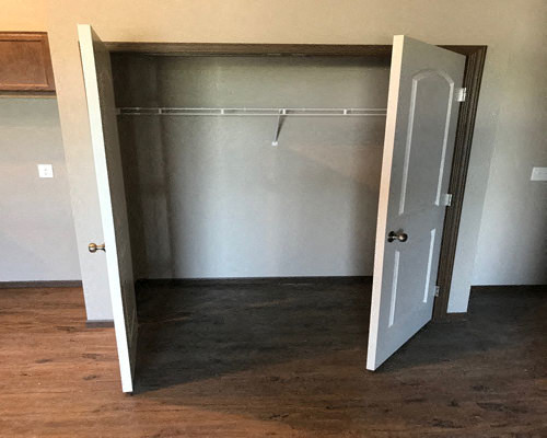 an empty room with a door open to a closet