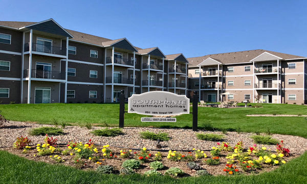 an apartment building with a sign in the middle of a flower garden