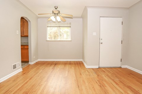 an empty living room with wood floors and a ceiling fan