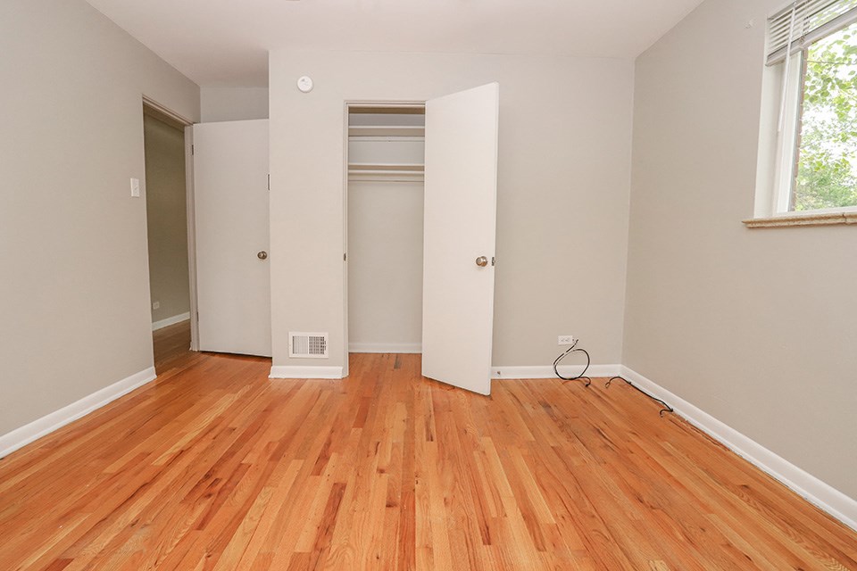 an empty room with wood floors and a closet