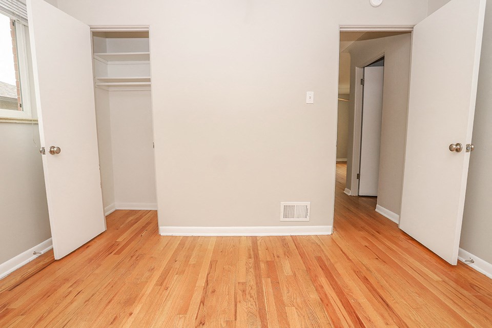 an empty room with wood flooring and white walls