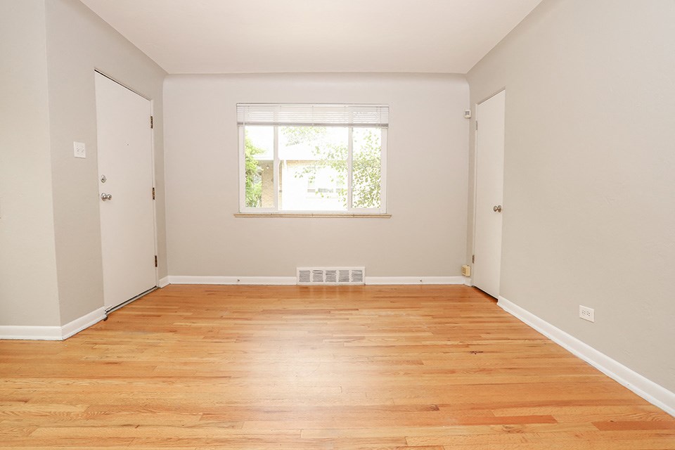 an empty room with wood floors and a window