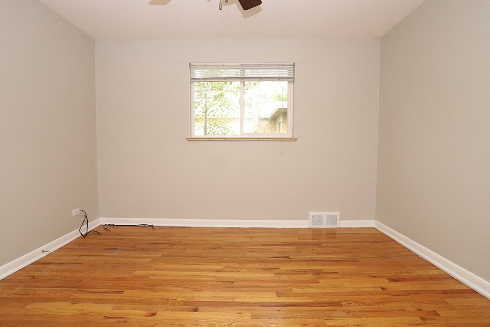 an empty room with wooden floors and a window