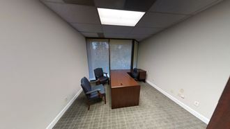 an empty office room with a desk and chairs