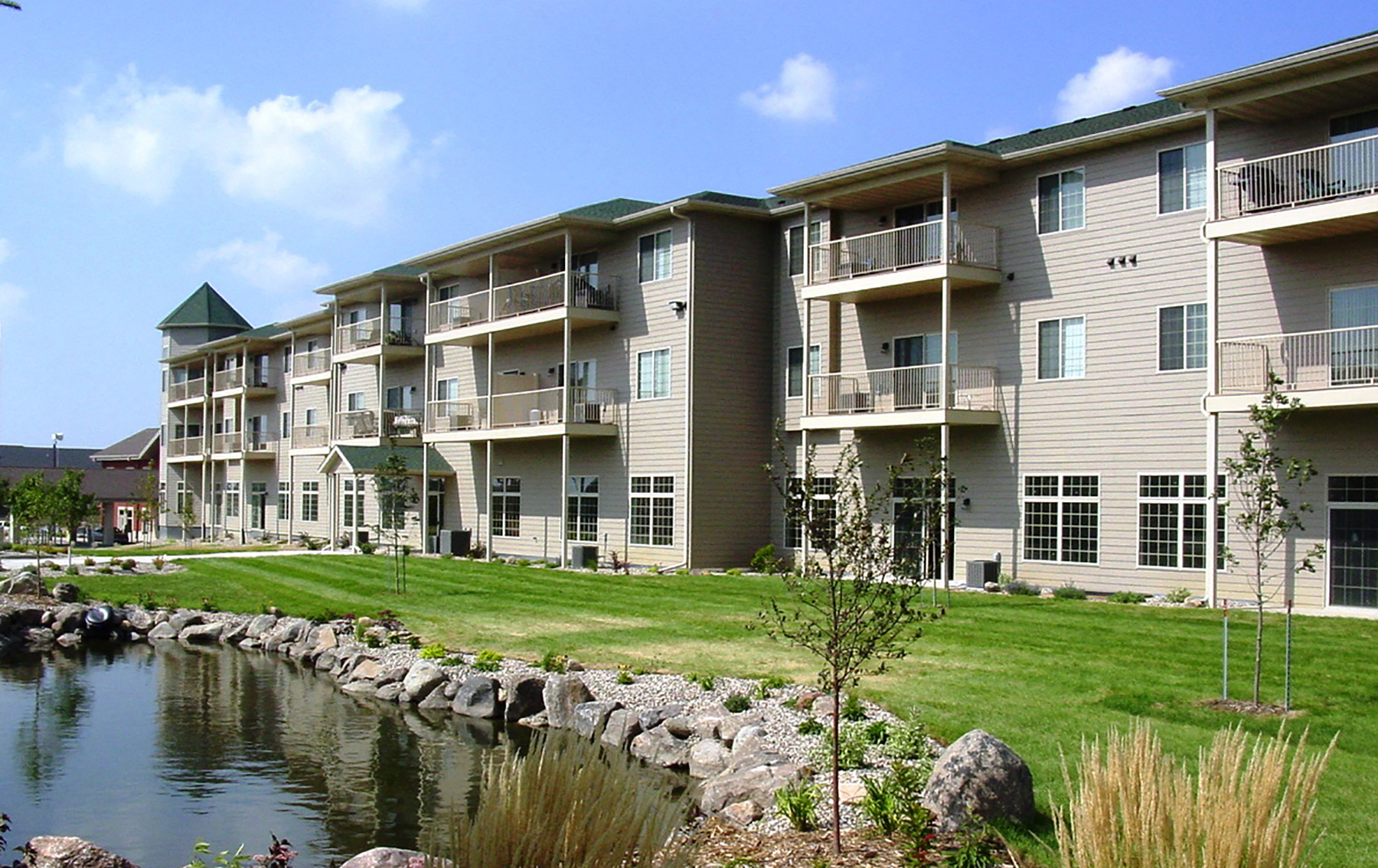 an apartment building with a pond in front of it