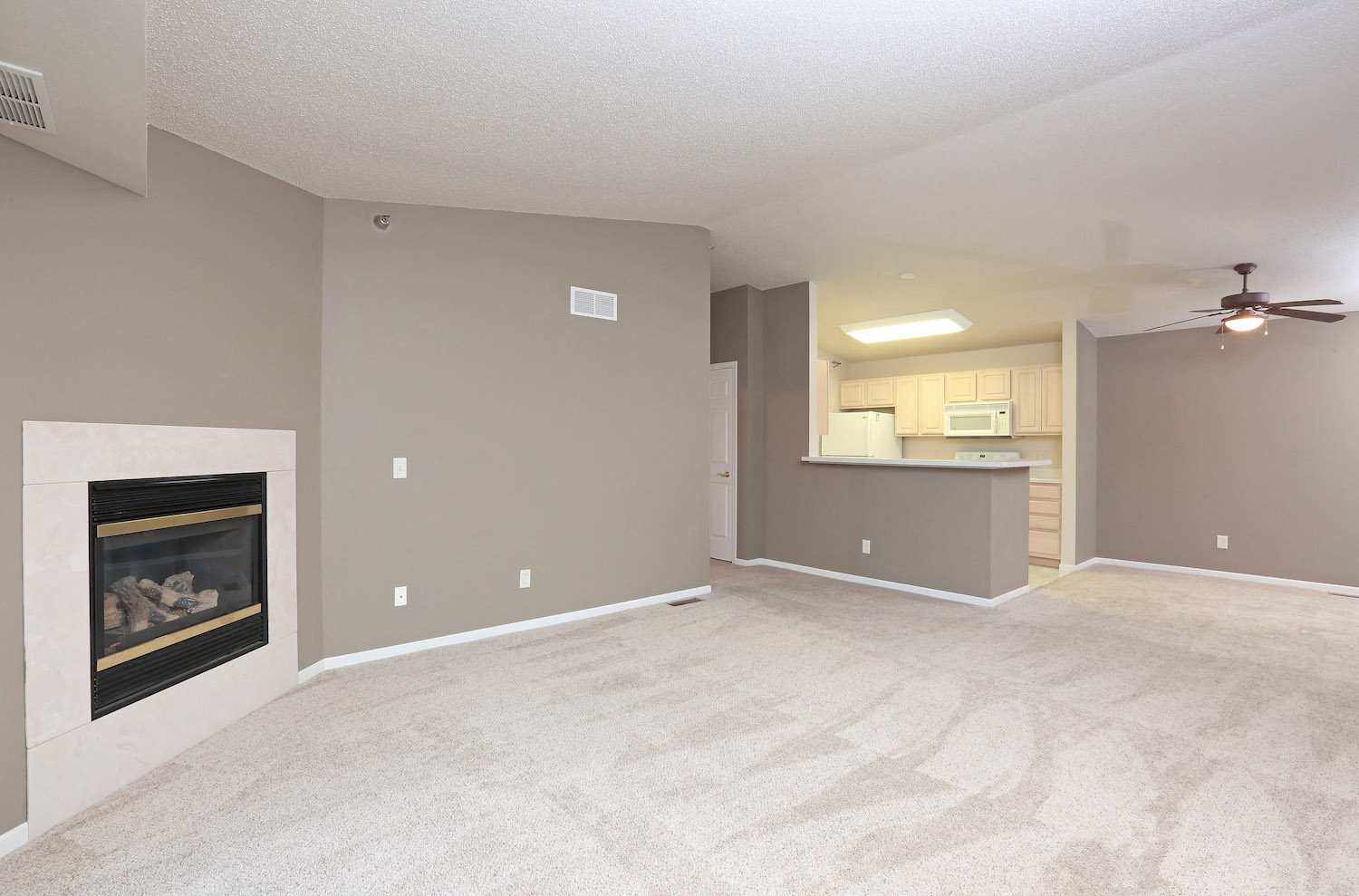 an empty living room with a fireplace and a kitchen