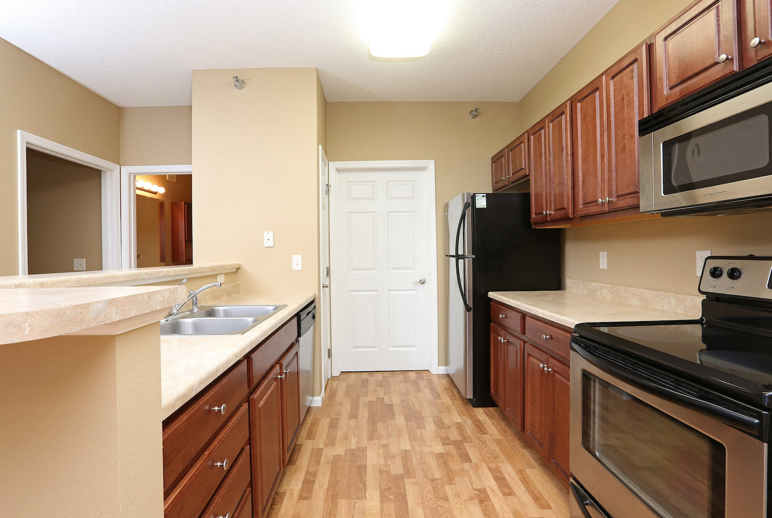 a kitchen with wooden cabinets and black appliances and a door