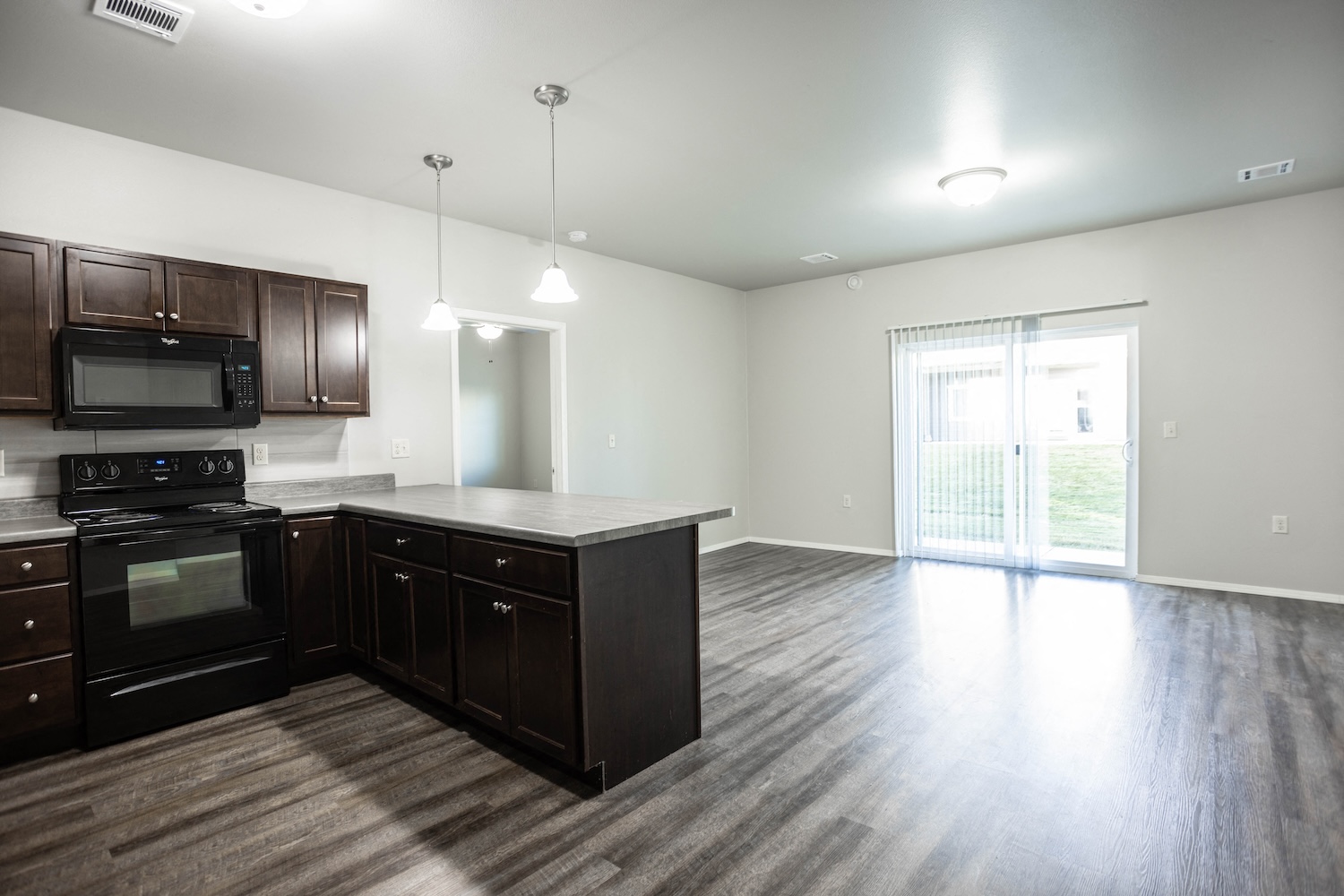 an empty kitchen and living room with wood flooring and