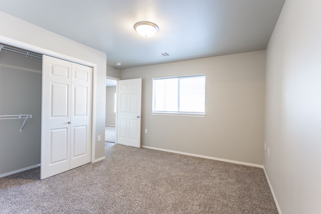 an empty room with a closet and a window and a door