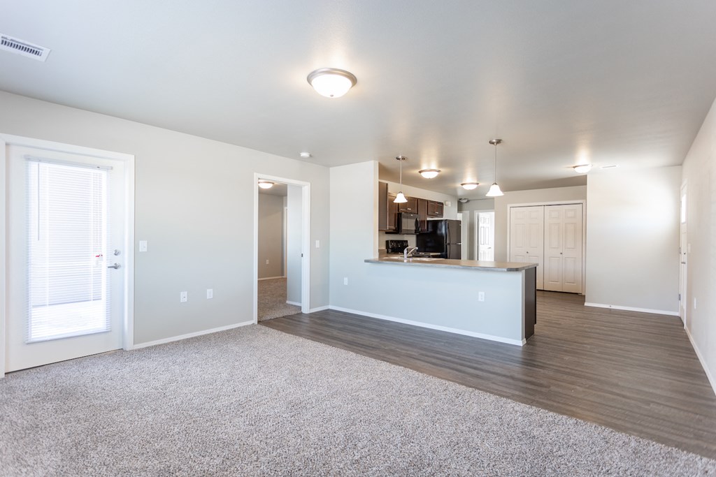 an empty living room and kitchen with white walls and wood flooring