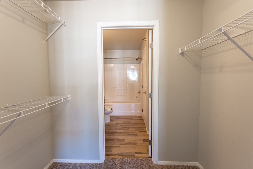 a walk in closet with a door open to a bathroom