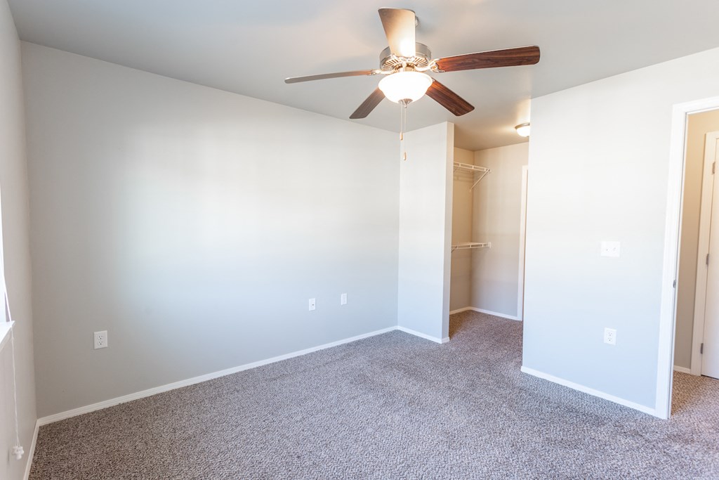 an empty room with a ceiling fan and a closet