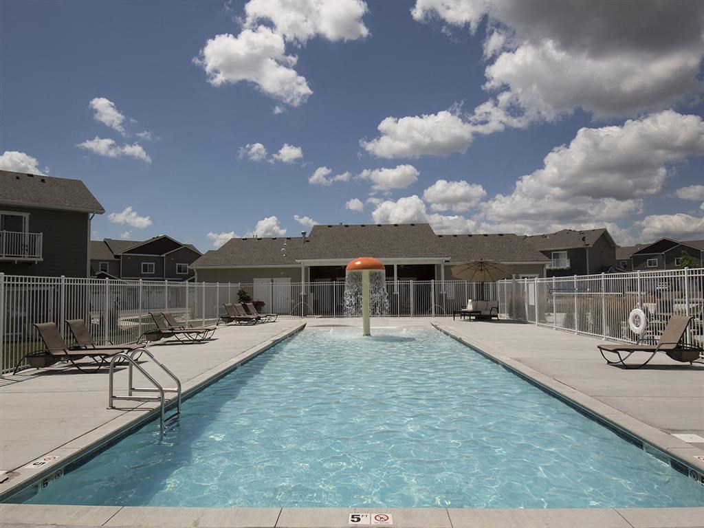 the pool is next to some chairs and a building