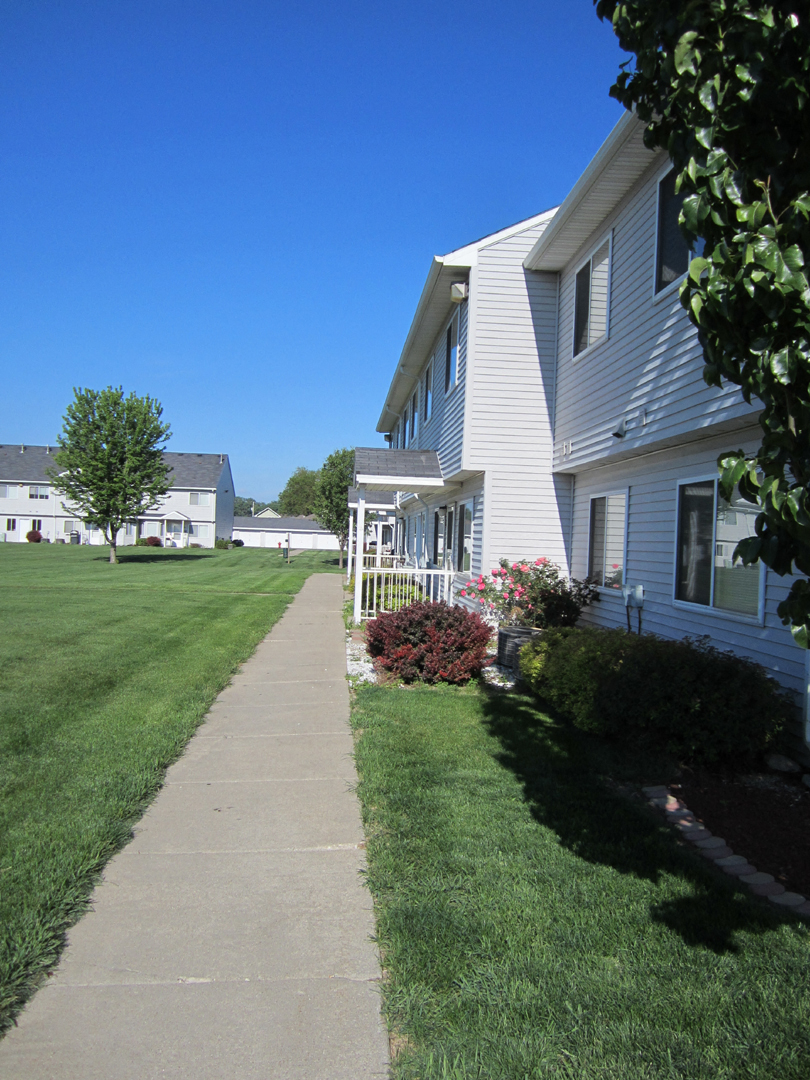 the side of a white house with a sidewalk in front of it