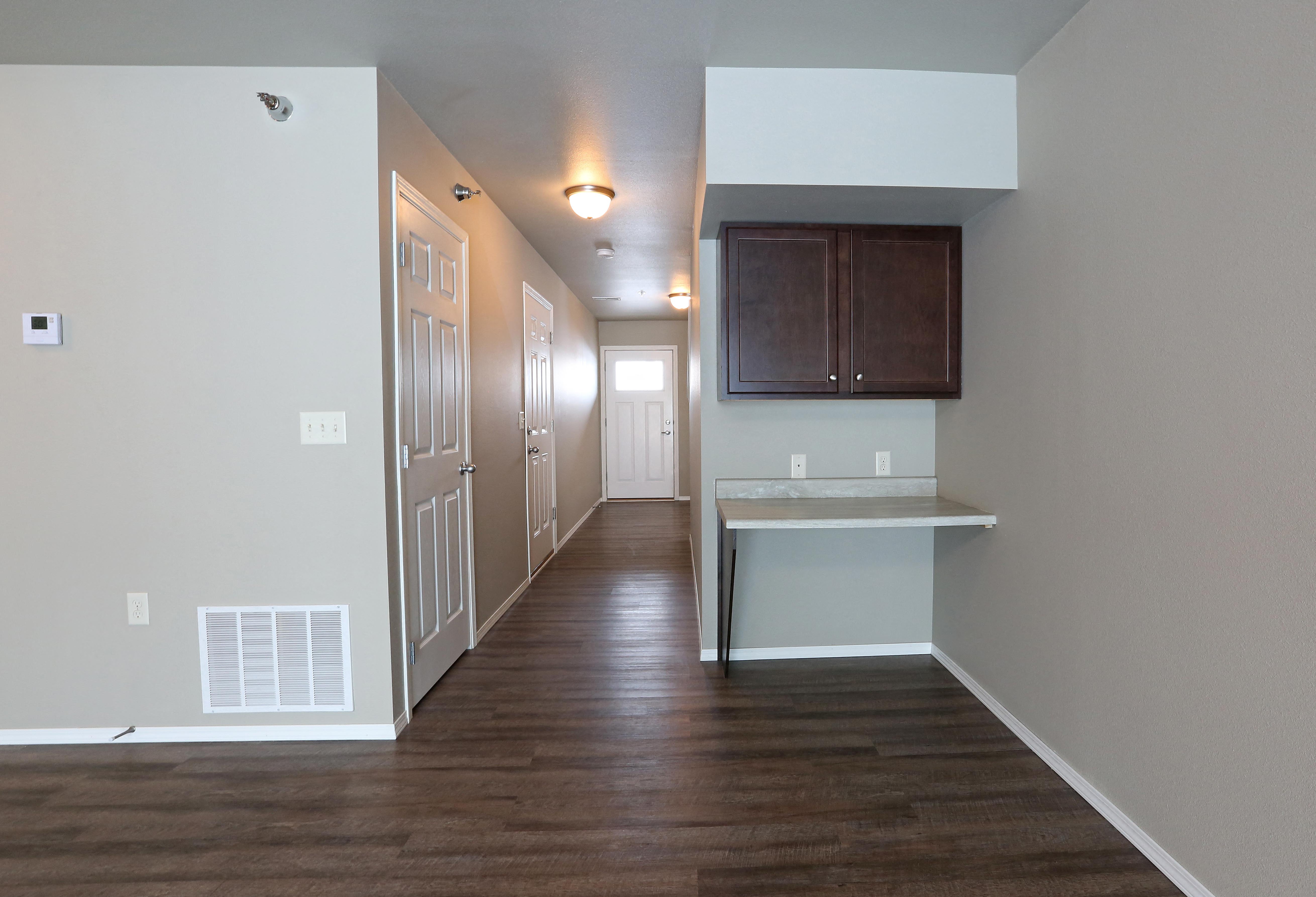 a long hallway with wood floors and white walls and a kitchen