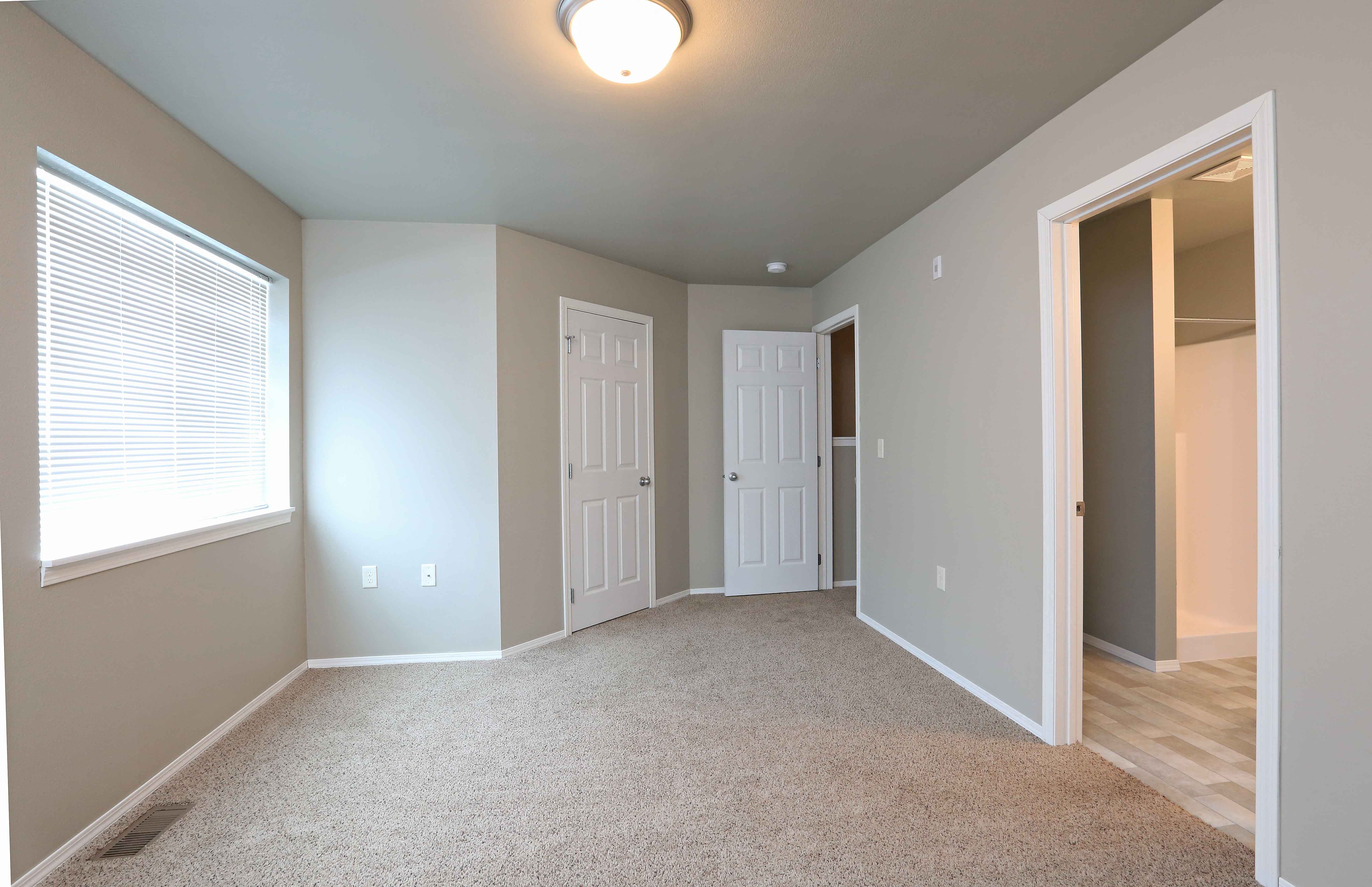 an empty room with two doors and a window