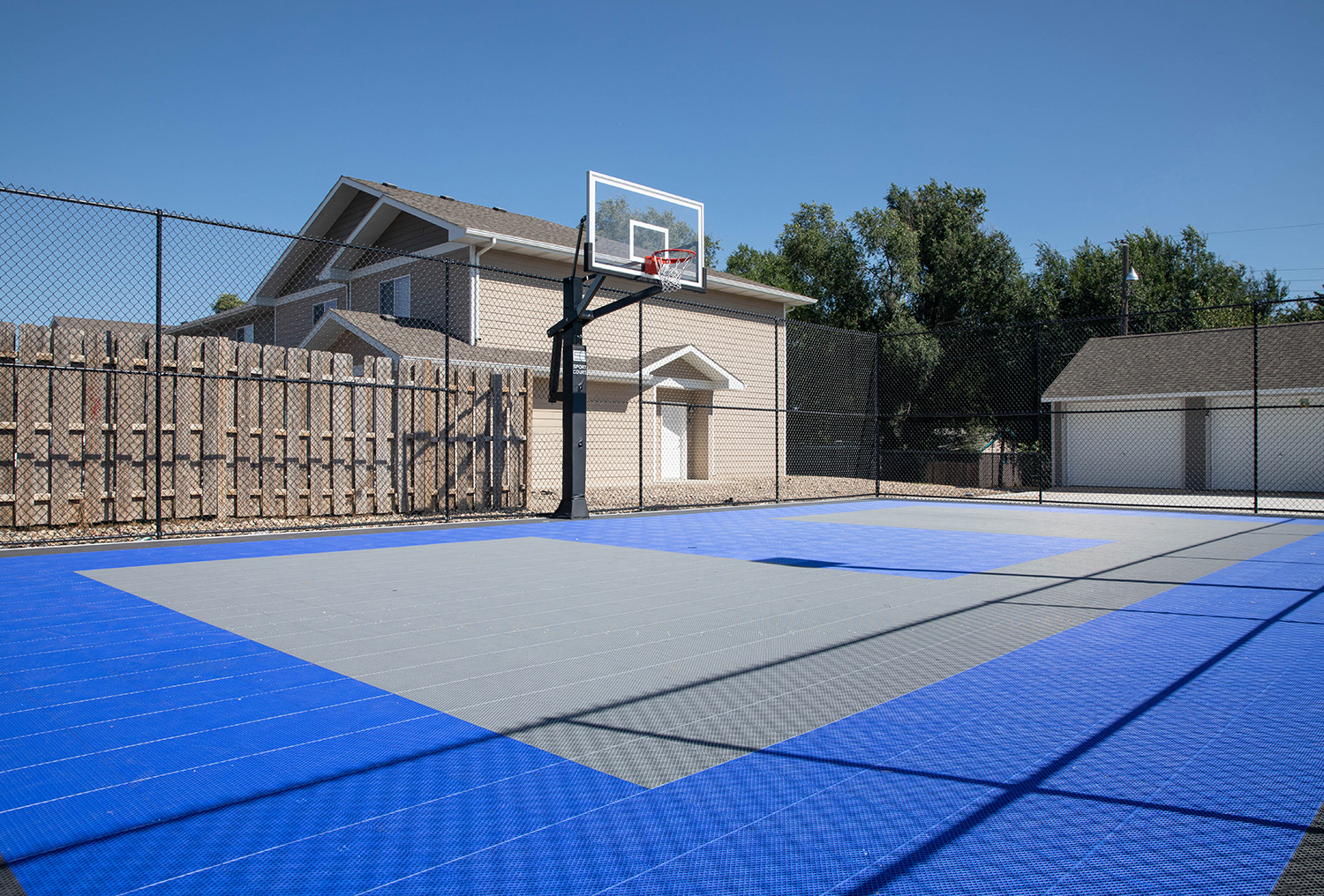 a basketball hoop on a blue court in front of a house