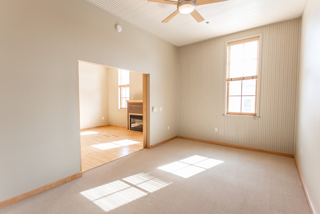 an empty living room with a ceiling fan and a window
