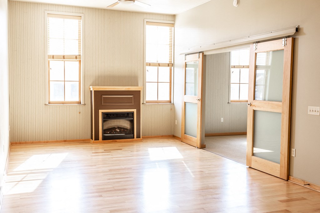 an empty living room with wood floors and a fireplace