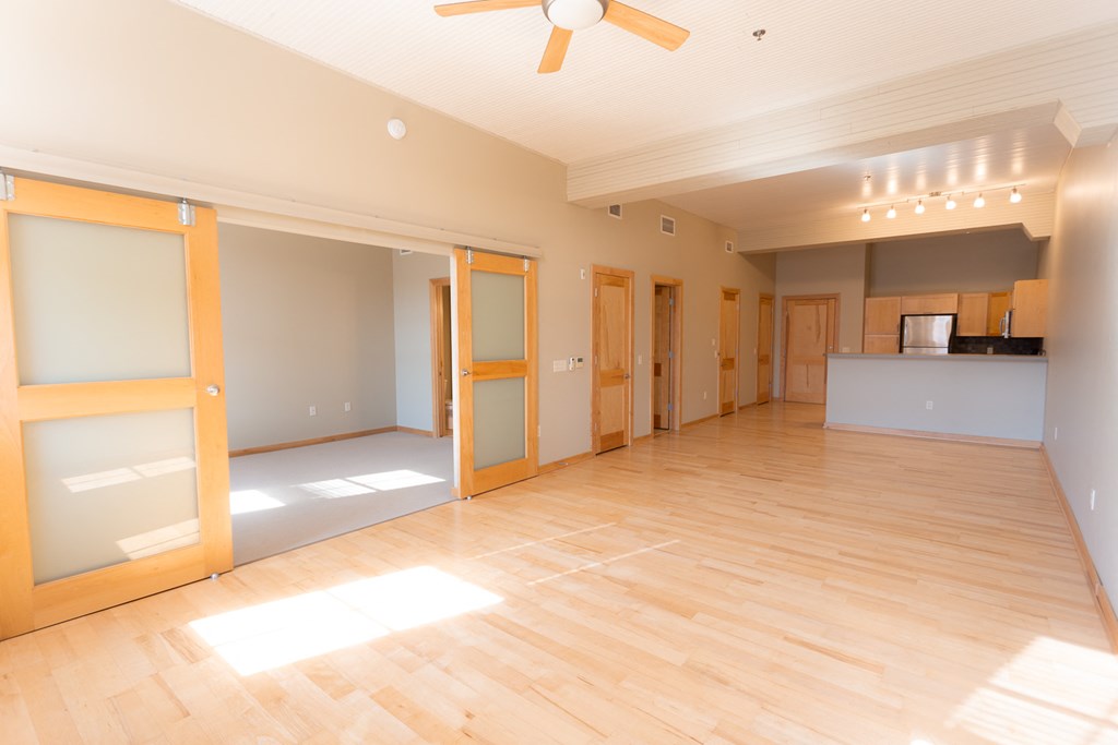 an empty living room with wooden floors and a ceiling fan