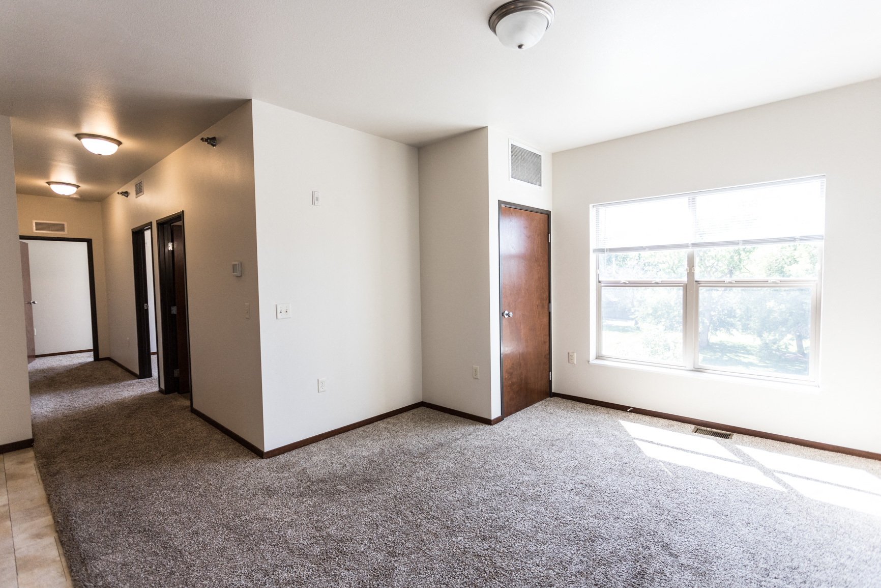 an empty living room with white walls and a window