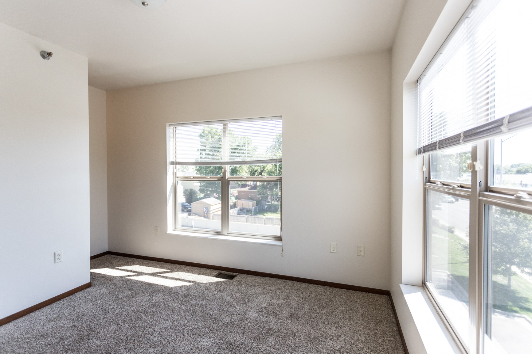 an empty living room with large windows and carpet