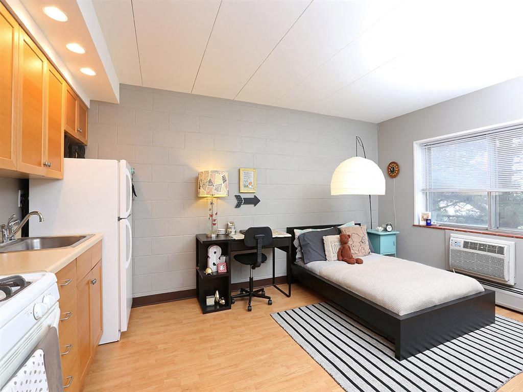 a small bedroom with a bed and a kitchen