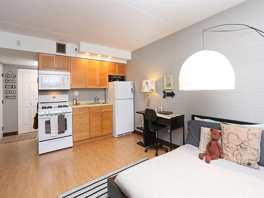 an open kitchen and living room with a bed and a teddy bear