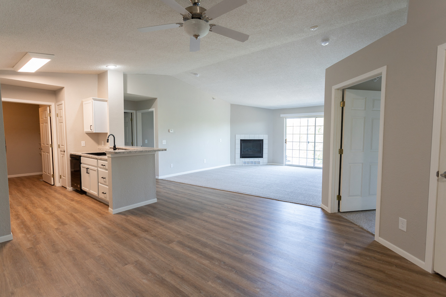 an empty living room and kitchen with a ceiling fan